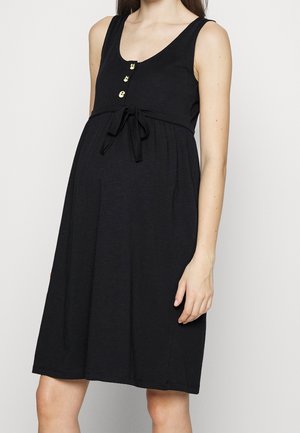 Czarna sukienka ciążowa z dekoltem w kształcie litery U, bez rękawów, ozdobiona złotymi guzikami i wiązaniem w talii. Miękki materiał i długość do kolan.