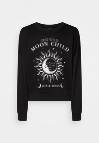 Sudadera corta negra con un diseño gráfico blanco de sol y luna, con el texto "MANTENTE SALVAJE, NIÑA DE LA LUNA" arriba y "SOL Y LUNA" abajo. Manga larga.