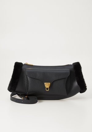 Sac en cuir noir avec une surface texturée, quincaillerie dorée, un rabat avant et des accents en fourrure noire à chaque extrémité. Comprend une bandoulière.