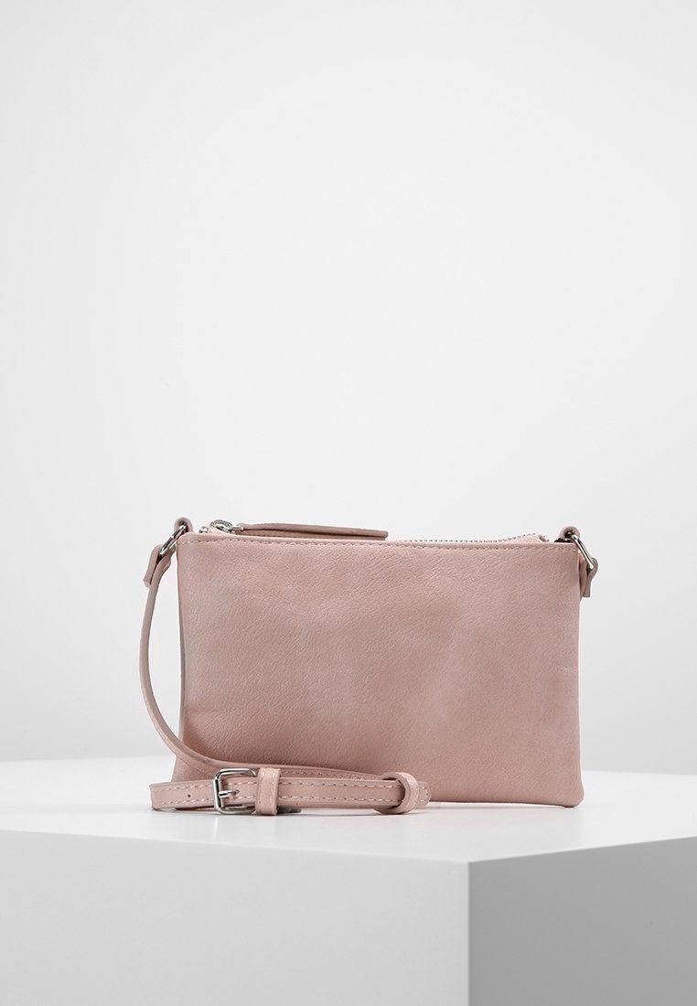 Měkká růžová kožená kabelka na zápěstí se stříbrným zipem a nastavitelným popruhem, vystavená na bílém podstavci na jednoduchém pozadí.