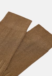 Calze scaldamuscoli marroni lavorate a maglia con una trama a costine, dotate di un bordo pieghevole e di un design della punta senza cuciture.