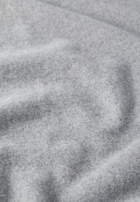 Tessuto grigio chiaro con una texture morbida e pelosa, caratterizzato da una superficie liscia e leggermente irregolare e da sottili variazioni di ombreggiatura.