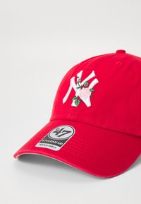 Cappellino da baseball rosso in cotone con logo ricamato e design floreale. Presenta una visiera curvata e una fascia regolabile con un'etichetta di marca.