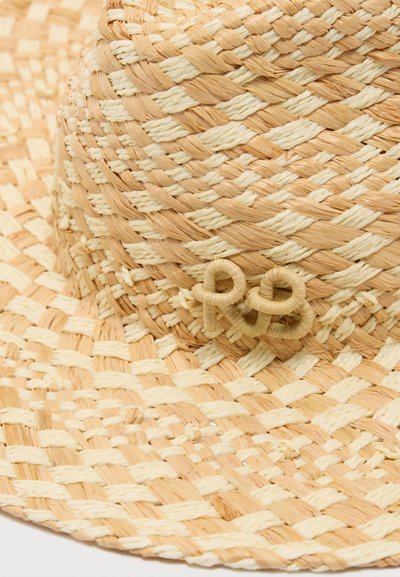 Καπέλο από πλεγμένο ψάθα με φαρδύ γείσο, σε φυσικές αποχρώσεις μπεζ και κρεμ, στολισμένο με φιόγκο σε σχήμα θηλιάς στη ζώνη.
