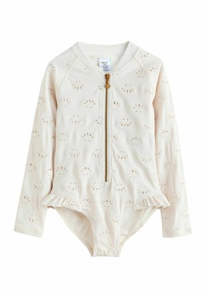 Cream long-sleeve baby swimsuit with embroidered shell patterns, front zipper with shell-shaped pull, and small ruffle details at hips.