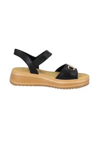 Sandale en cuir noir avec une large sangle, des bandes réglables et un accent doré. La semelle à plateforme présente une base en caoutchouc beige et un motif texturé.