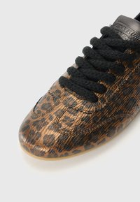 Baskets en cuir bronze avec un motif léopard, dotées de lacets noirs et d'une texture lisse. Bout rond et détails surpiqués.