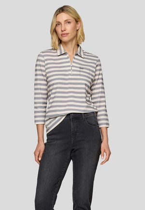 Gestreiftes langärmliges Poloshirt in Hellgrau und Dunkelgrau, mit einem halben Reißverschluss und einer kleinen Brusttasche, kombiniert mit schwarzen Jeans.