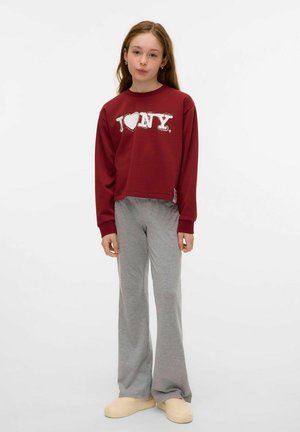 Sweat à manches longues rouge avec le graphique "I ❤️ NY". Pantalons de sport gris à jambe large, chaussons beiges. Texture lisse, coupe décontractée.