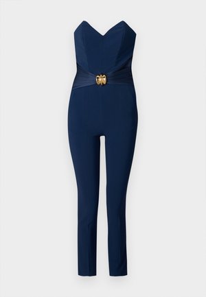 Tuta marina con scollo a cuore, corpino aderente e gambe affusolate. Presenta una fascia testurizzata orizzontale e una ferramenta circolare dorata in vita.