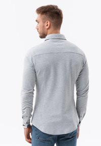 Grijze langemouwen shirts met een kraag, met een gladde textuur en knoopmanchetten, gecombineerd met blauwe spijkerbroek.