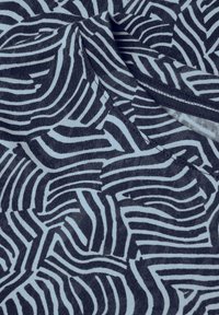 Tissu bleu marine avec un motif rayé ondulé en bleu clair. Texture douce avec un col rond et des détails de couture visibles.