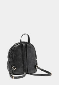 Mochila negra de cuero acolchada con correas ajustables y asa en la parte superior sobre un fondo gris claro liso.