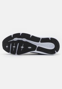 La suola di una scarpa atletica in bianco e nero presenta un design a tratti segmentati in gomma, con scanalature per una migliore aderenza e flessibilità. Materiale liscio e testurizzato.