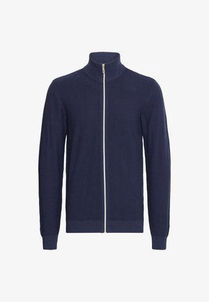 Cárdigan de punto en navy con cremallera y cuello alto, puños y dobladillo acanalados. Presenta una cremallera plateada y un patrón texturizado en toda la prenda.