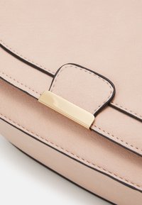 Borsa in ecopelle rosa con una texture liscia, caratterizzata da cuciture nere e una chiusura a patta con fibbia in metallo color oro.