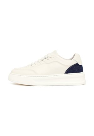 Biały niski sneaker z grubą podeszwą i granatowym materiałowym detalem na pięcie, widoczny z boku na białym tle.