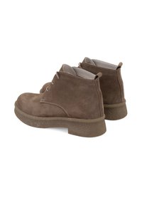 Braune Wildleder-Ankle Boots mit runder Zehe, zwei Ösen und einer dicken, strukturierten Gummisohle. Weiches Innenfutter ist oben sichtbar.