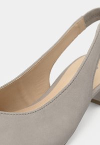 Chaussure slingback en daim beige avec un petit talon, dotée d'un design découpé et d'une doublure intérieure lisse. Bout arrondi et détails de couture soignés.