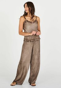 Costum două piese, de culoare maro, cu un top din dantelă și pantaloni evazați, realizat dintr-un material texturat, ușor.