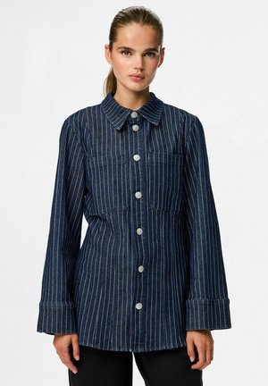 Donker denim overhemden met witte verticale strepen, met een kraag, twee borstzakken en wijde mouwen. Geweven stofafwerking.