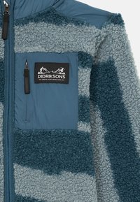 Fleecejacke mit durchgehendem Reißverschluss, in einem blauen und grauen Streifenmuster, aus strukturiertem Stoff und mit einem schwarzen Logopatch auf der Brust.