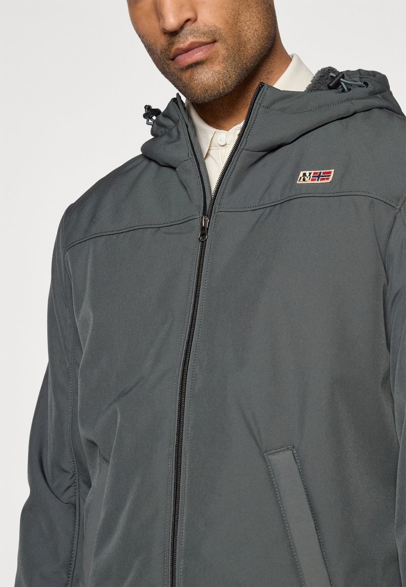 Veste à capuche grise avec une fermeture éclair à l'avant, dotée d'un logo en patch, de poches latérales et d'une doublure intérieure texturée. Finition en tissu lisse.