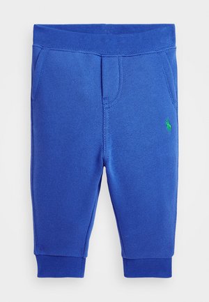 Pantalones de chándal de algodón azul con cintura y puños acanalados. Presenta dos bolsillos laterales y un pequeño emblema de logo verde. Textura suave en todo su diseño.