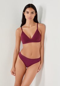 Bralette de couleur vin et culottes assorties. Tissu doux avec une texture lisse, présentant un design triangulaire et des bretelles étroites.