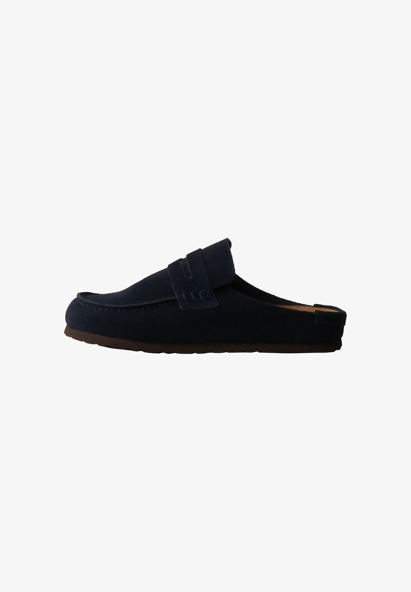 Mocassin bleu foncé à enfiler avec un petit talon et un détail de bride sur le dessus, présenté de côté sur fond blanc.