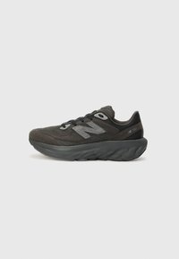 Chaussure de sport noire avec tige en mesh et superpositions texturées. Équipée d'une semelle épaisse et rembourrée ainsi que d'accents réfléchissants. Système de laçage pour un ajustement optimal.