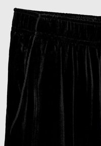 Pantalones de pijama de terciopelo negro con cintura elástica y bolsillos laterales. Presentan una textura suave y un acabado liso.