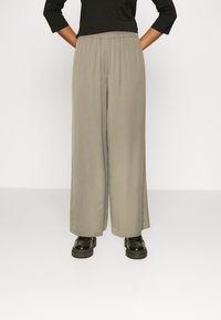Light gray wide-leg pants with an elastic waistband, made from soft fabric, paired with black platform shoes.