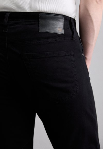 Μαύρα τζιν με υφάσματος από δερμάτινη πατέντα με ανάγλυφο λογότυπο, σχέδιο πέντε τσεπών και διακριτική ραφή στις πίσω τσέπες.