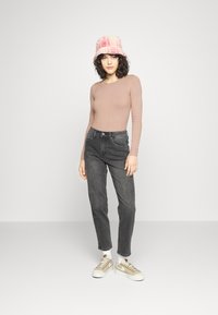 Ribota garo piedurkņu tops gaismi brūnā krāsā, augstiem jostasvietā melnie džinsi, beige un baltie sporta apavi, rozā raibie kausa cepure. Vienkāršs, ikdienišķs apģērbs.