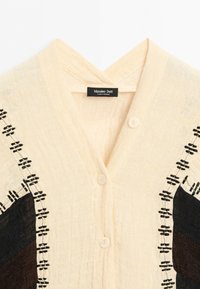 Beige buttoned blouse with black and brown geometric stitched patterns on shoulders and upper sleeves, labeled Massimo Dutti.