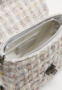 Borsa in tweed con un motivo multicolore testurizzato, hardware in argento e un ampio interno dotato di un compartimento con cerniera.