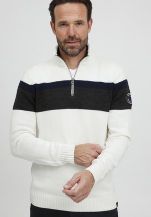 Weißer Strickpullover mit dunkelgrauen und Marineblauen horizontalen Streifen, Reißverschlusskragen, gerippten Bündchen und Saum. Mit einem Logo-Patch am Ärmel.