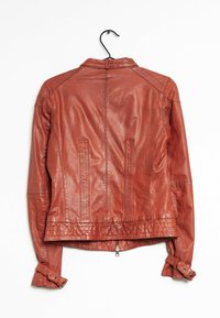 Giubbotto di pelle color arancione bruciato, che mette in risalto un design aderente, taglio dritto e polsini con bottone a pressione. Presenta cuciture in vista e tasche laterali.