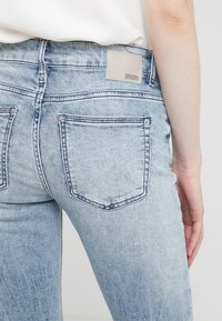 Bleka ljusblå denim jeans med smal passform, som har två bakfickor och en etikett med "DRYKORN" på midjebandet.