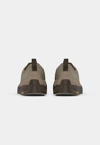 Brown and green hiking shoes with a suede upper, flat sole, and prominent Vibram logo at the heel. Features a pull tab for easy wear.