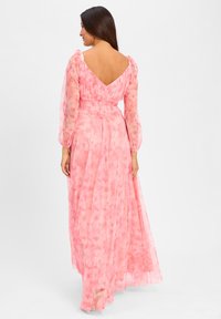 Maxi dress in soft pink fabric with floral patterns, puff sleeves, a V-back, and smocked waist for fitted silhouette. Elegant, flowing design.