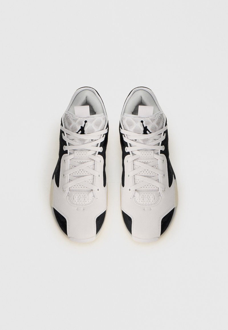 Zapatillas deportivas blancas y negras con un upper texturizado, que cuentan con cierre de cordones, cuello acolchado y detalles en la entresuela.