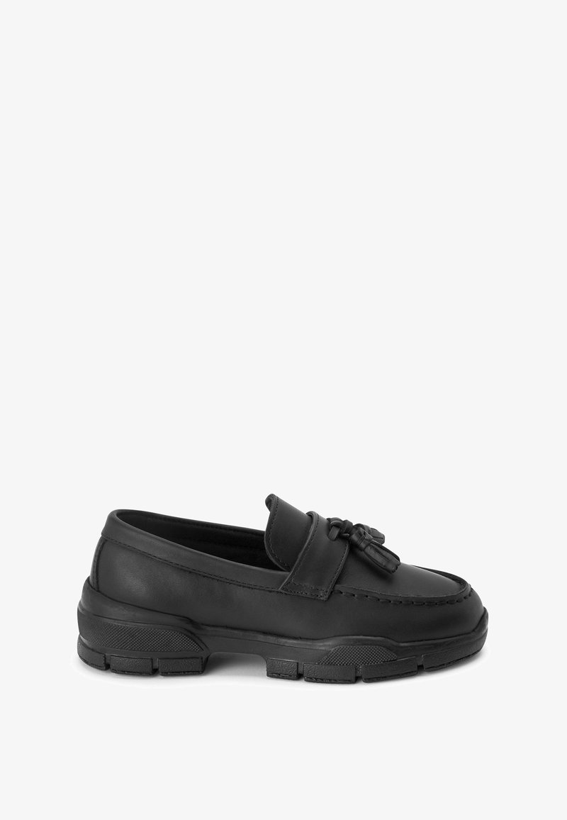Mocassin en cuir noir avec pampilles, semelle épaisse en caoutchouc et couture moc toe, conçu pour un port décontracté ou semi-formel.