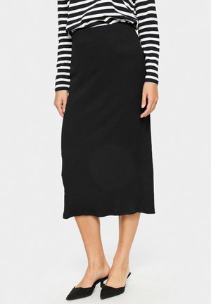Black midi skirt made of textured fabric. Fitted waistband with a smooth finish, hemline falling just above the ankle. Paired with a striped top.