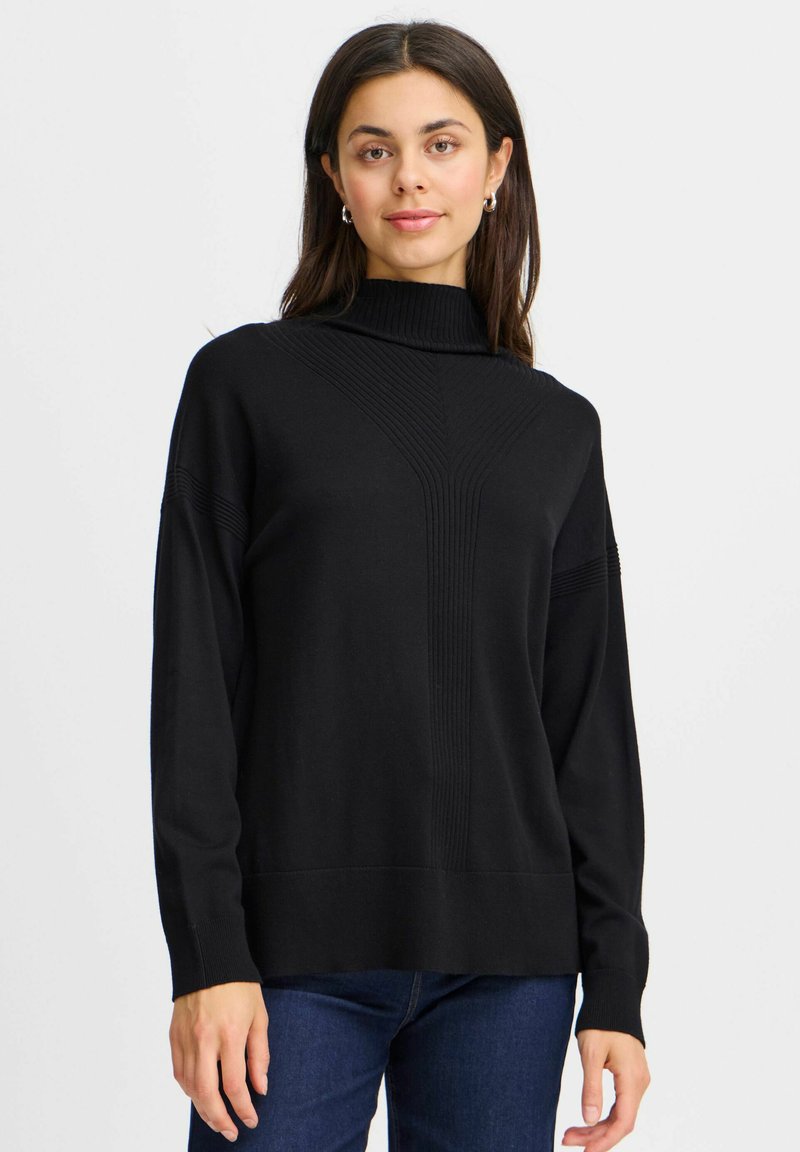 Črn pulover s turtleneck iz ribane tkanine in navpičnimi črtami, z ohlapnim krojem in dolgimi rokavi, stiliziran z modrimi kavbojkami.