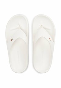 Chanclas de goma blancas con una textura suave, que presentan una tira en forma de Y y un pequeño logotipo tricolor en el costado.