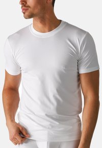 Hvid kortærmet t-shirt lavet af glat bomuldsstof. Klassisk rund halsudskæring med en tætsiddende pasform og ren kant. Ingen synlige mønstre eller logoer.