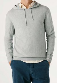 Felpa con cappuccio grigio chiaro realizzata in tessuto morbido, con polsini e orlo a costine, dall'aspetto stratificato sopra una camicia con colletto.