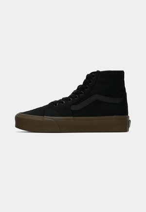Sneakers alte nere in suede, con suola in gomma, lacci rotondi e una striscia laterale in un tessuto più scuro. Parte superiore testurizzata con cuciture.